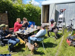 Teilnehmende des Vereins „Trockenbau – das Zirkuswagenprojekt e.V.“ bei einer gemeinsamen Pause während handwerklicher Arbeiten an einem Zirkuswagenprojekt